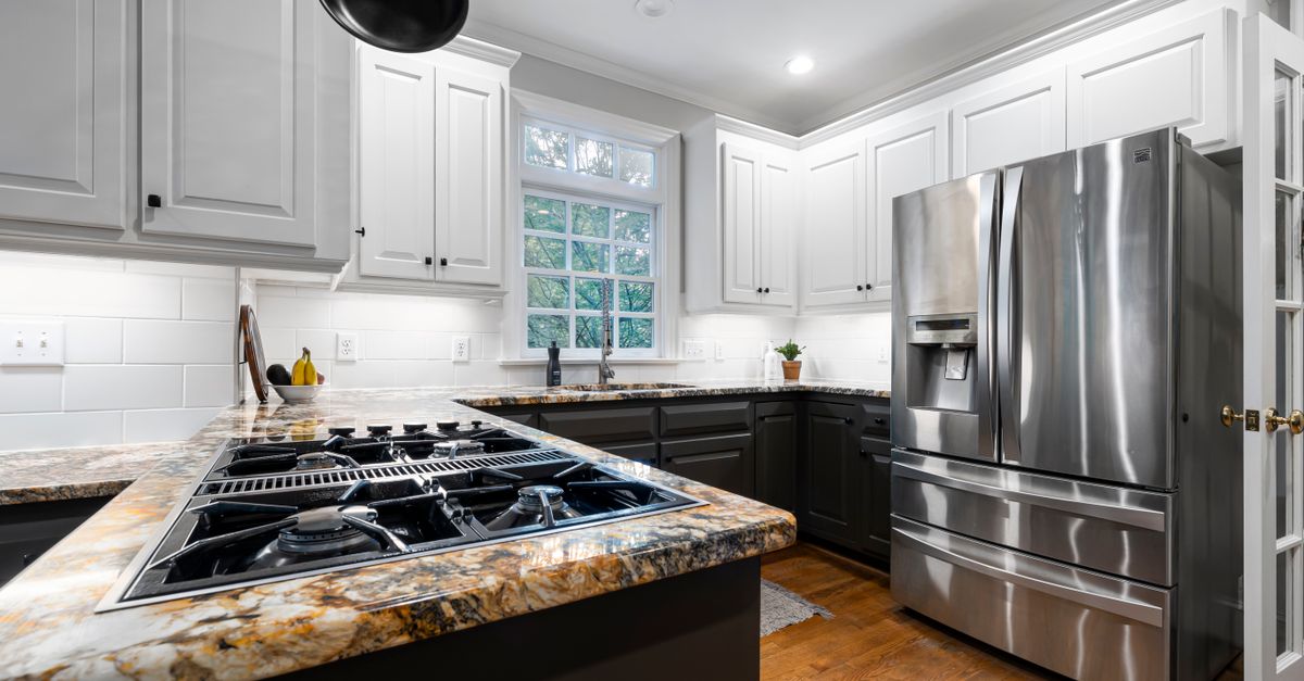 Bright modern kitchen with stainless steel fridge and elegant countertops.