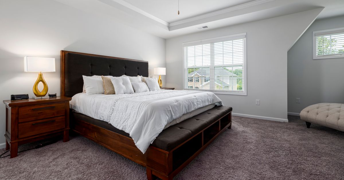 Elegant bedroom with wooden bed frame and soft lighting for a serene atmosphere.