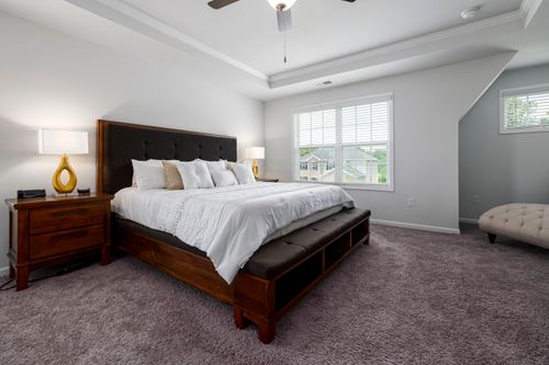 Free Elegant bedroom with wooden bed frame and soft lighting for a serene atmosphere. Stock Photo
