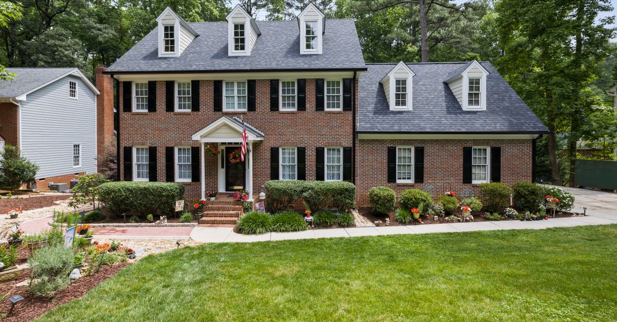 Stunning colonial-style brick house with lush garden and classic architecture.