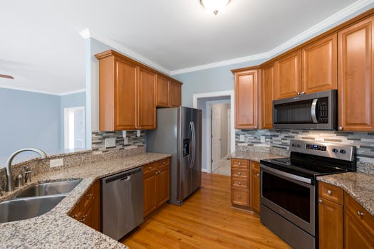 Spacious kitchen interior featuring granite countertops, stainless steel appliances, and wooden cabinets.