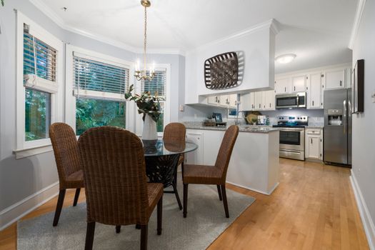 Contemporary dining area with wicker chairs and modern kitchen setup, filled with natural light.