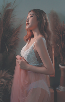 A graceful woman posing in white lingerie and pink fabric, exuding elegance.