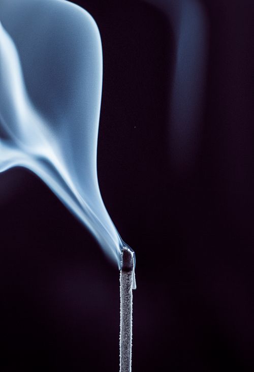 Free A detailed close-up of an incense stick with smoke gracefully rising against a dark background. Stock Photo