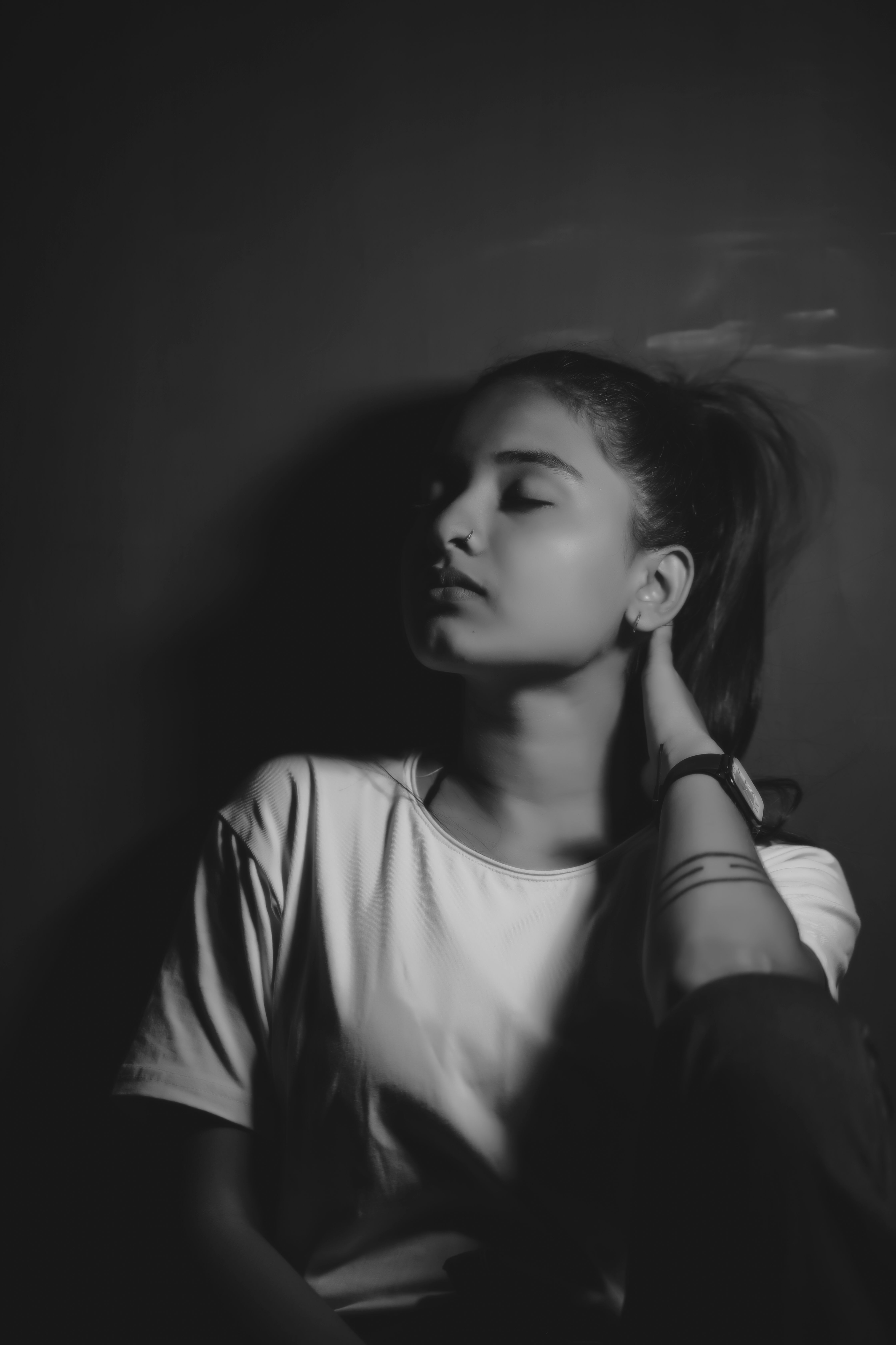 A contemplative young woman poses in moody black and white, evoking introspection.