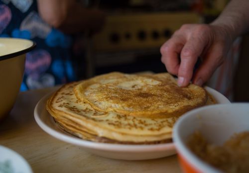 Free A stack of homemade pancakes being touched by a hand in a cozy kitchen setting. Stock Photo