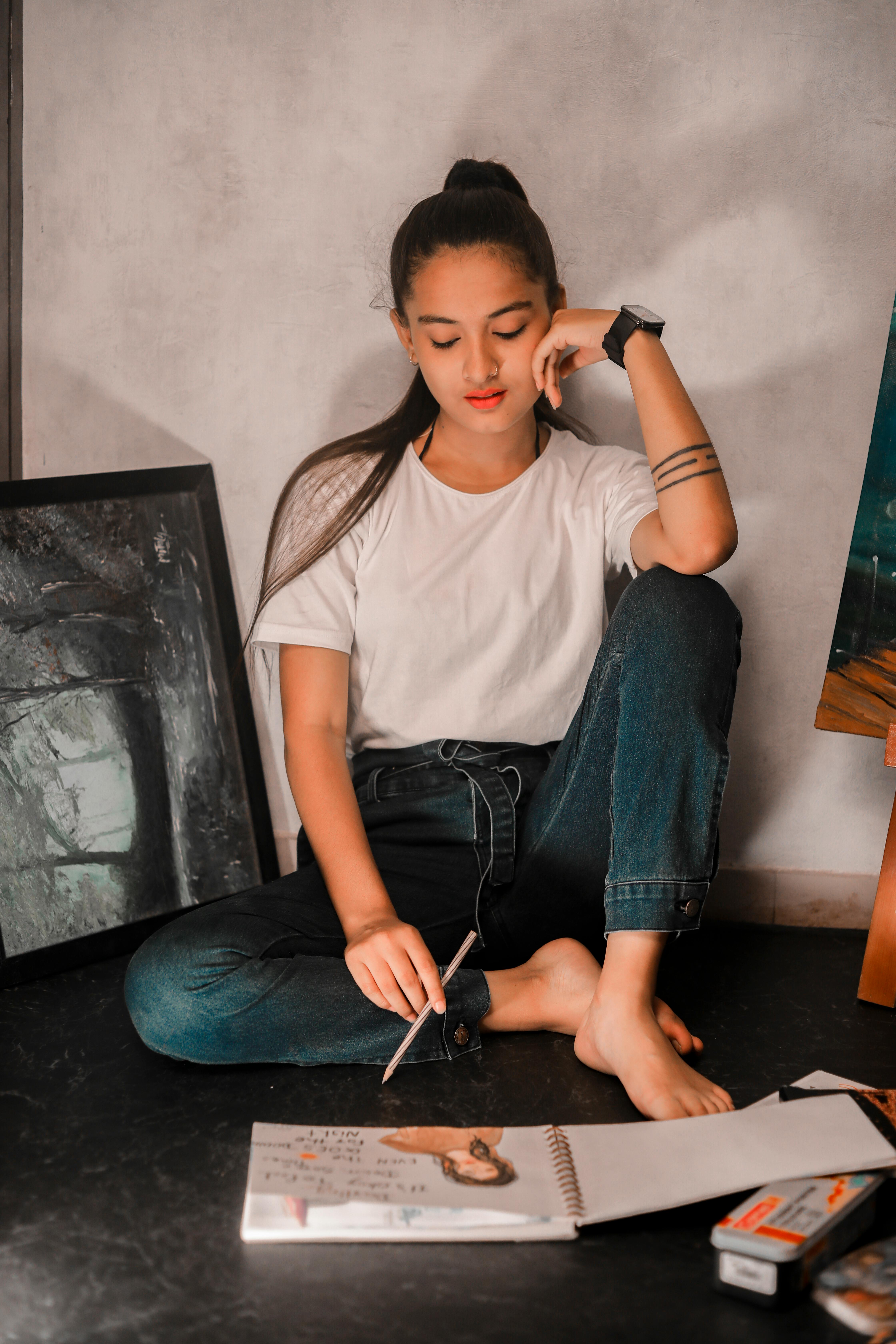 Young woman artist sitting in studio, reflecting over her sketchbook.