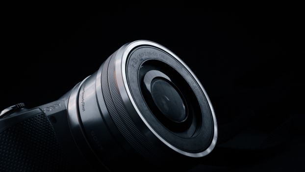 A detailed close-up of a camera lens set against a black background, highlighting precision and technology.