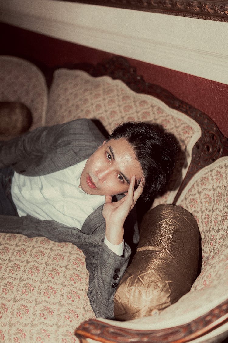 Young Man In Grey Suit Lying On Vintage Sofa