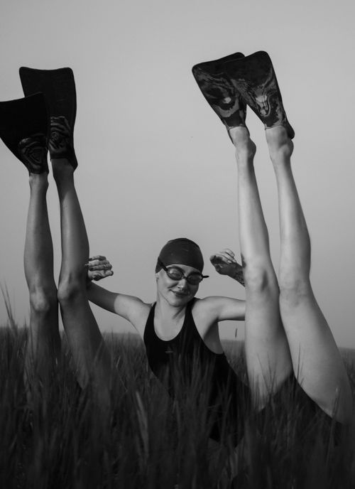 Free Black and white image of swimmers with flippers having fun in a grassy field. Stock Photo