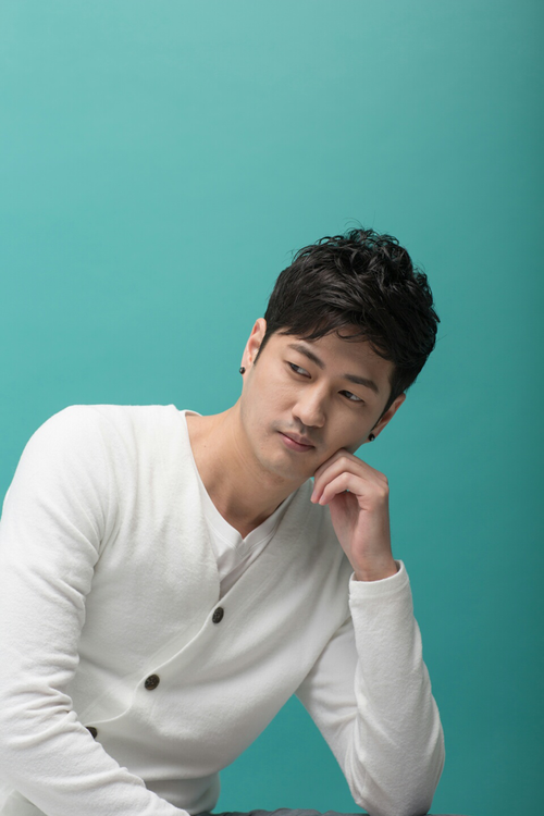 Free Portrait of a stylish Asian man posing thoughtfully indoors with a teal background. Studio shot. Stock Photo