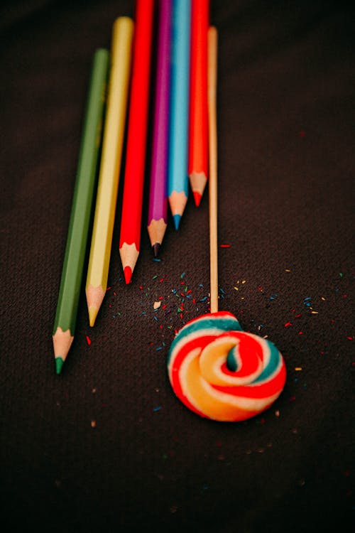 Free Colored Pencils and a Lollipop over a Textile Surface Stock Photo