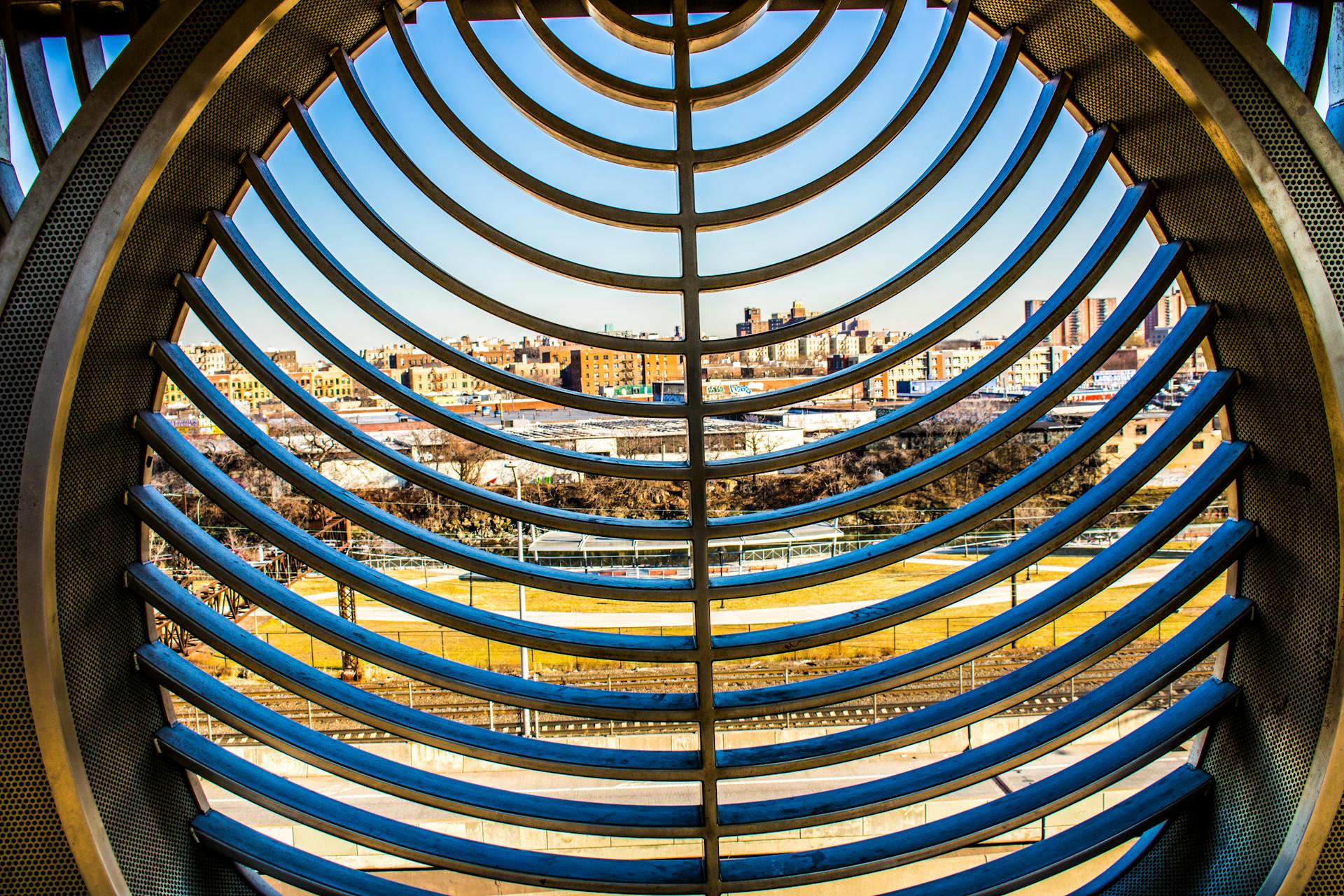 View of city skyline framed by a modern metal grid structure, showing architectural innovation.