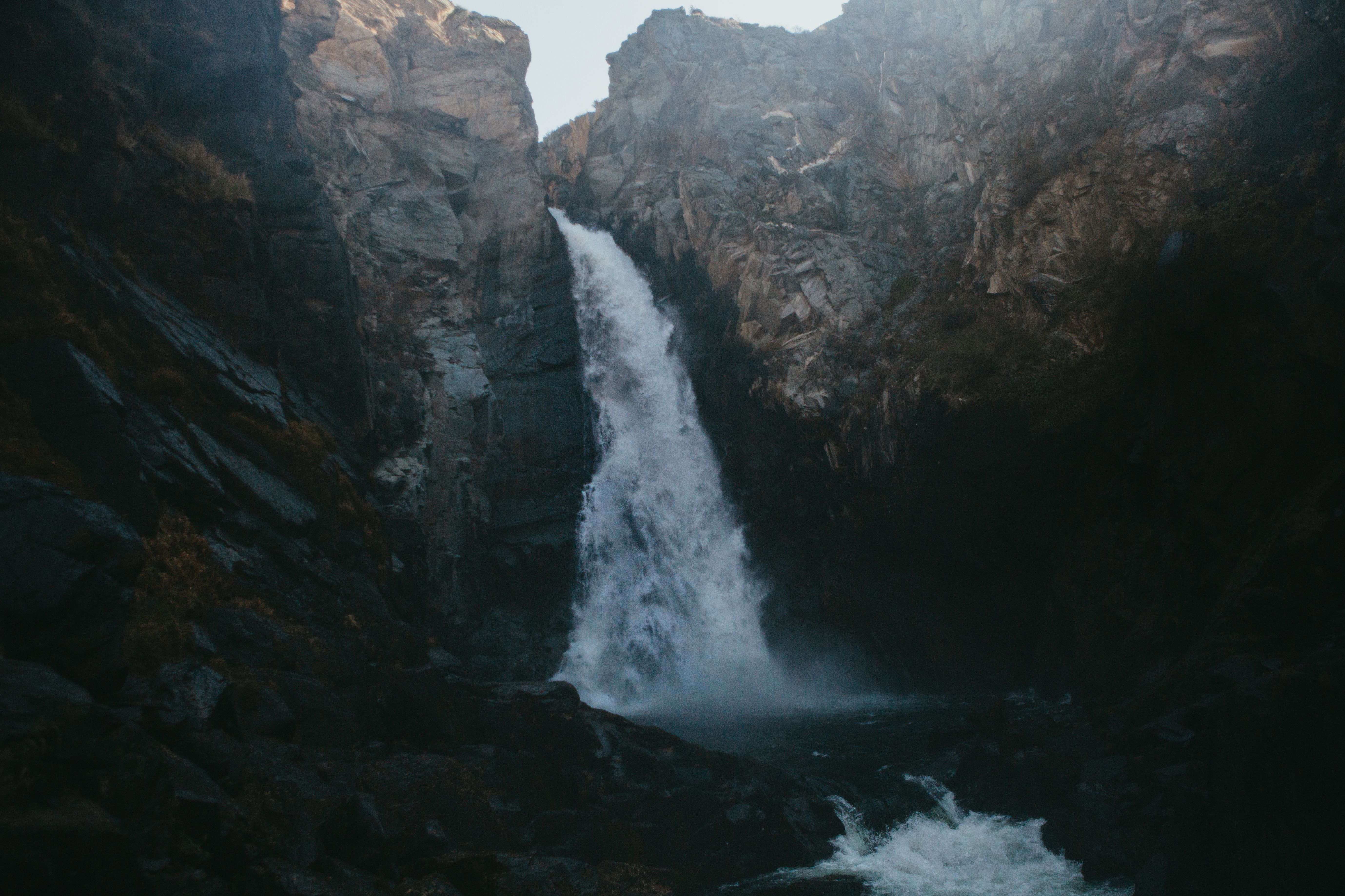A stunning waterfall cascades down rocky cliffs within a serene mountain landscape.