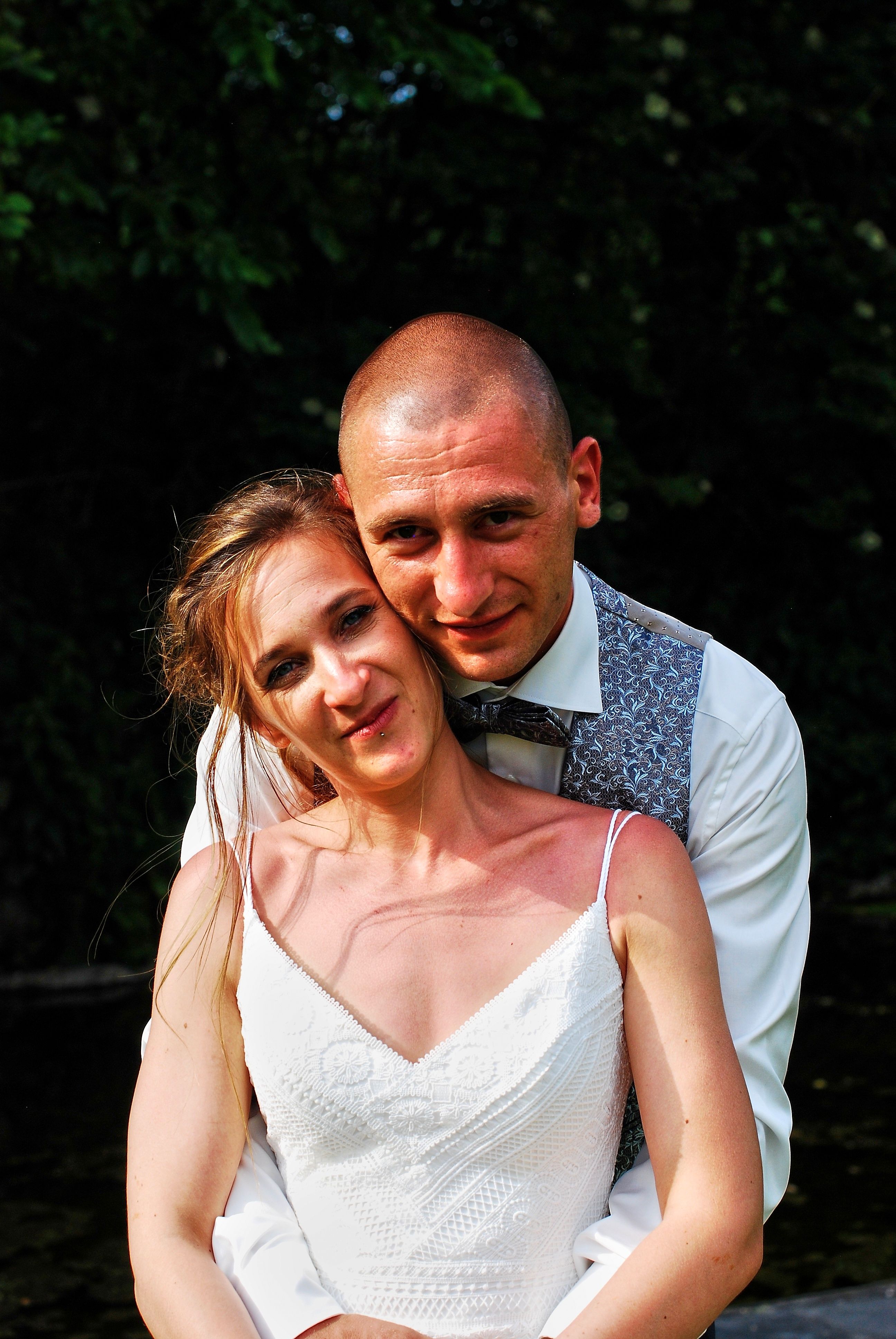 Happy newlywed couple embracing joyfully outdoors in sunlight.