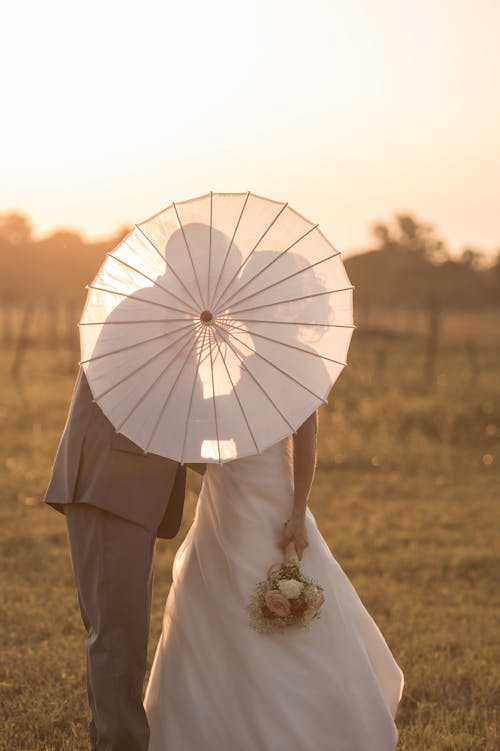 Couple Standing on Grass Field Covered with Umbrella