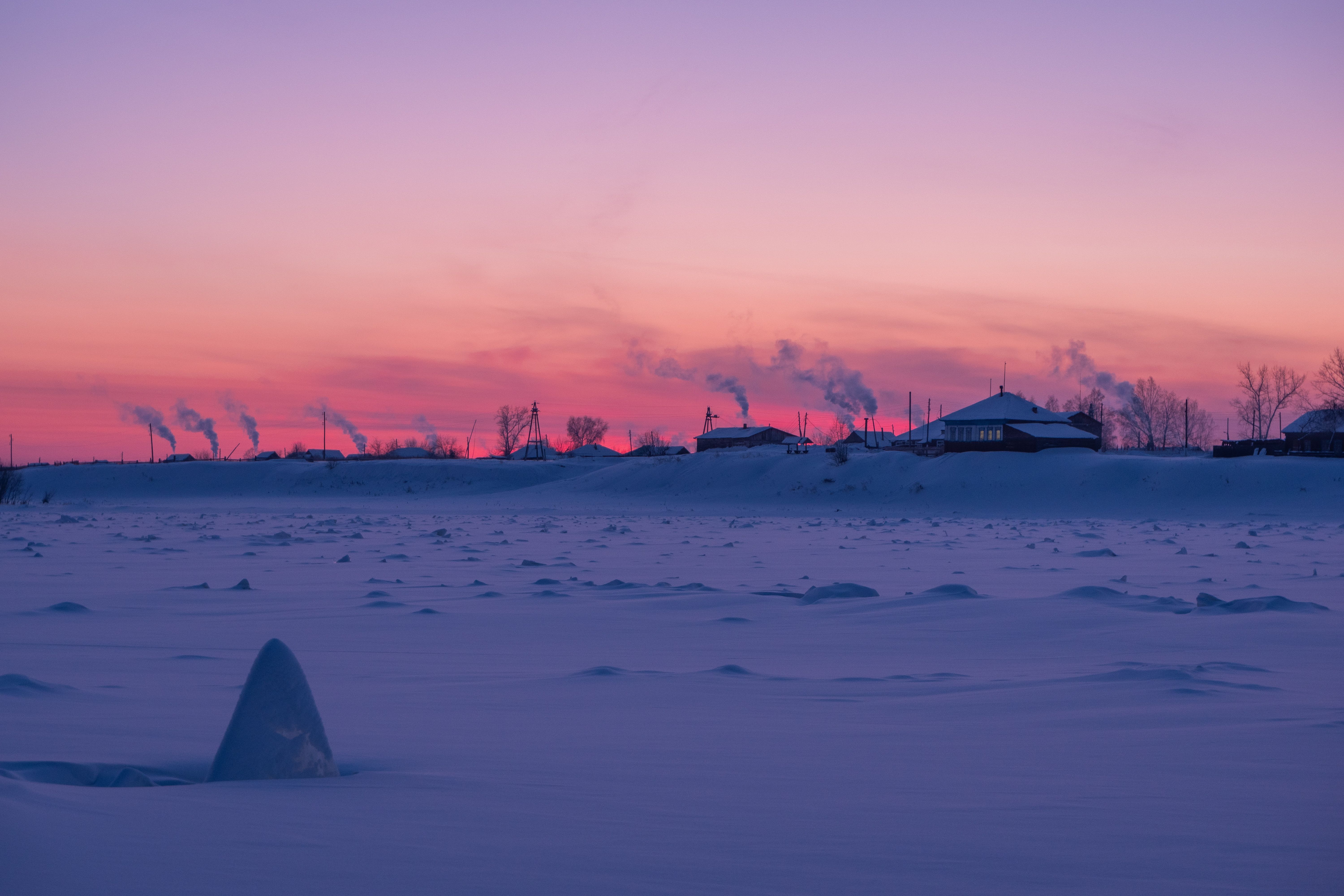 Smoke rising over a village at dusk
