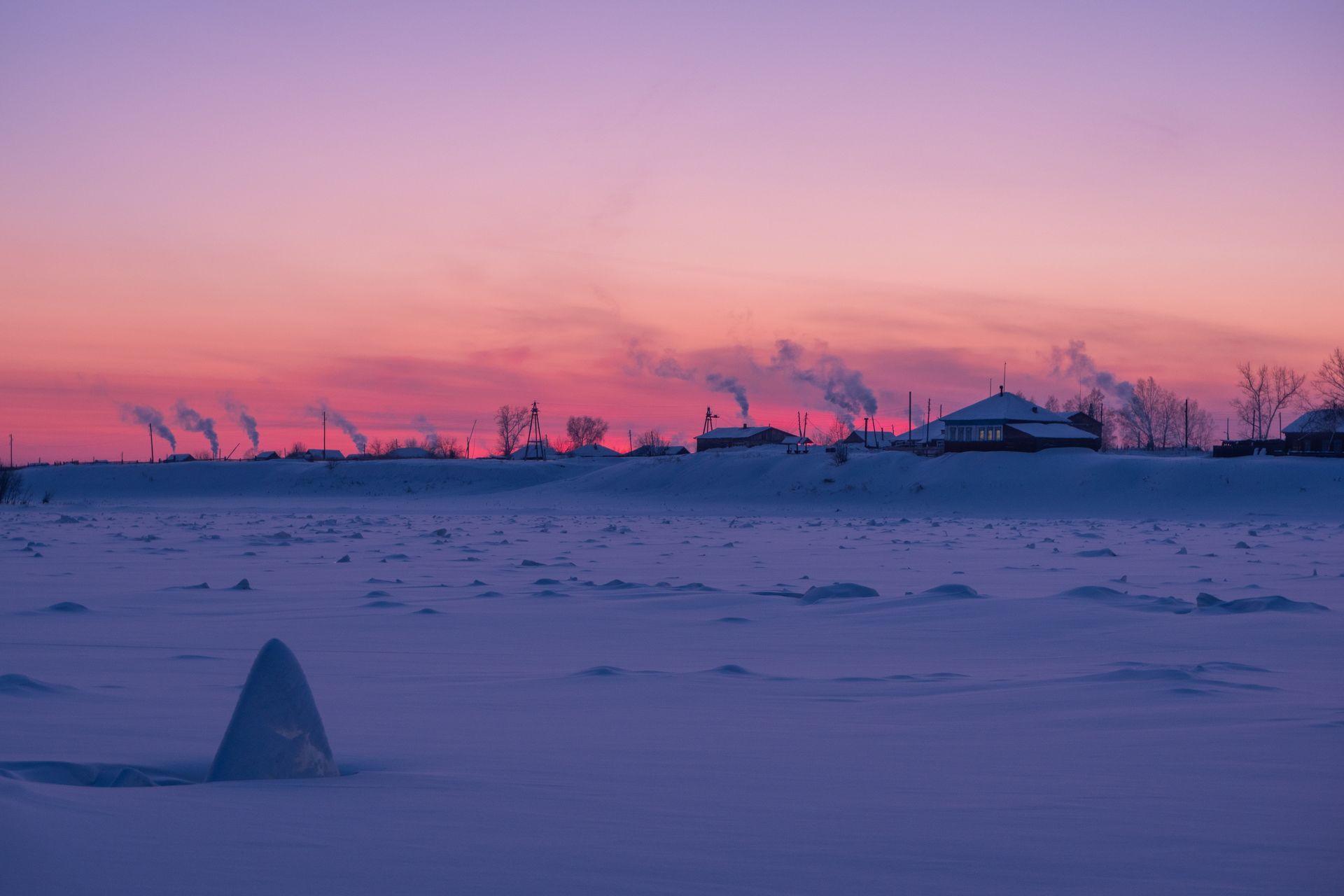 Smoke rising over a village at dusk