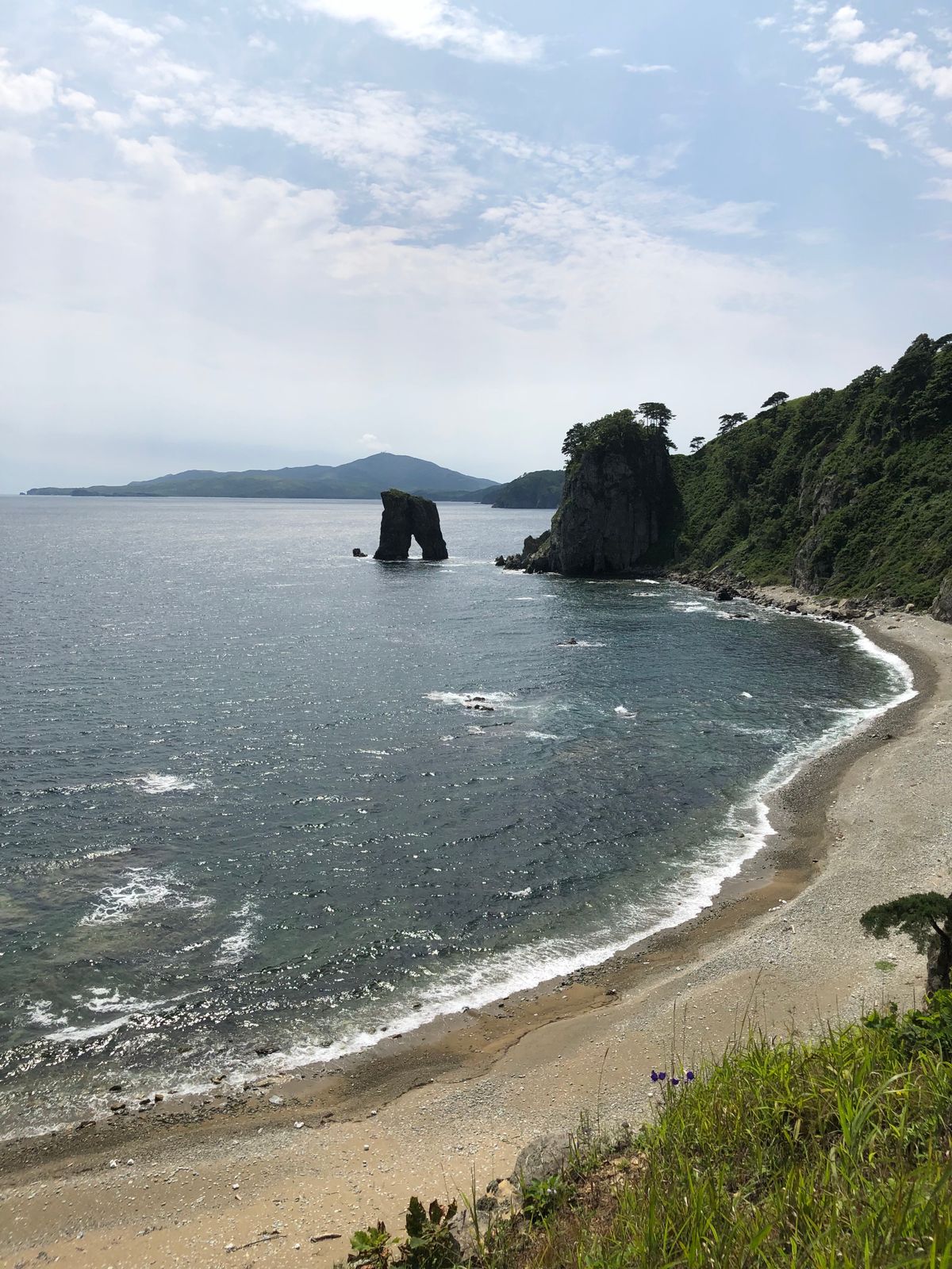 Serene Japanese coastline with rocky formations, lush vegetation, and calm ocean waters