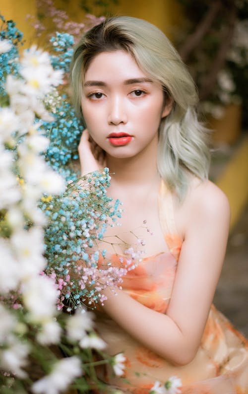 Girl in Orange Floral Dress Posing Near the Bouquet of Flowers