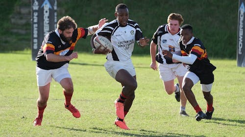 Athletes Playing Rugby on Green Grass Field