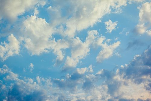 Free A vast expanse of blue sky filled with fluffy white clouds on a sunny day. Stock Photo