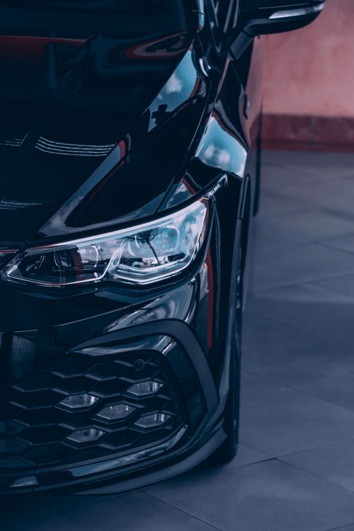 Free Detailed view of a luxury car's headlight and grille in an urban environment. Stock Photo