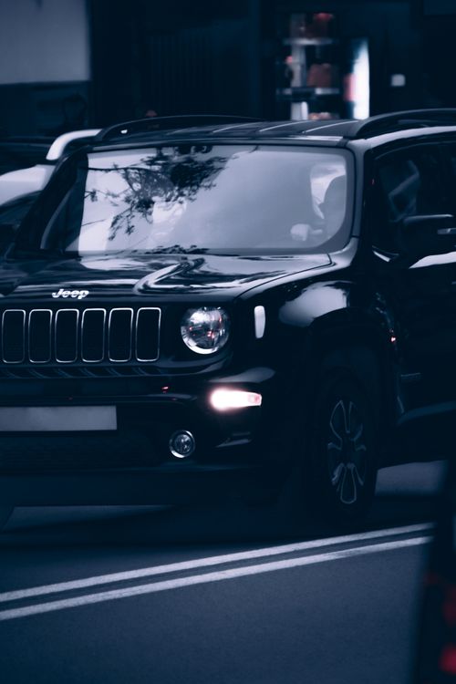 Free Black Jeep SUV driving on urban roads with reflections on windshield in city setting. Stock Photo