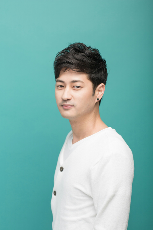 Free Profile portrait of an East Asian man in a white cardigan against a teal background. Stock Photo