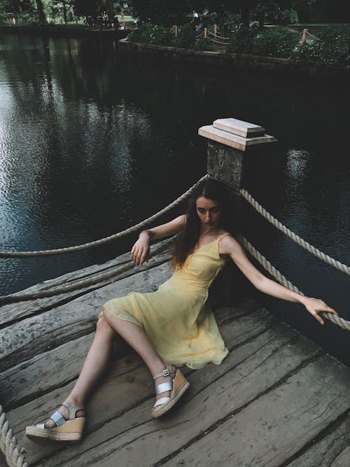 Woman in Yellow Dress Sitting on Wooden Dock
