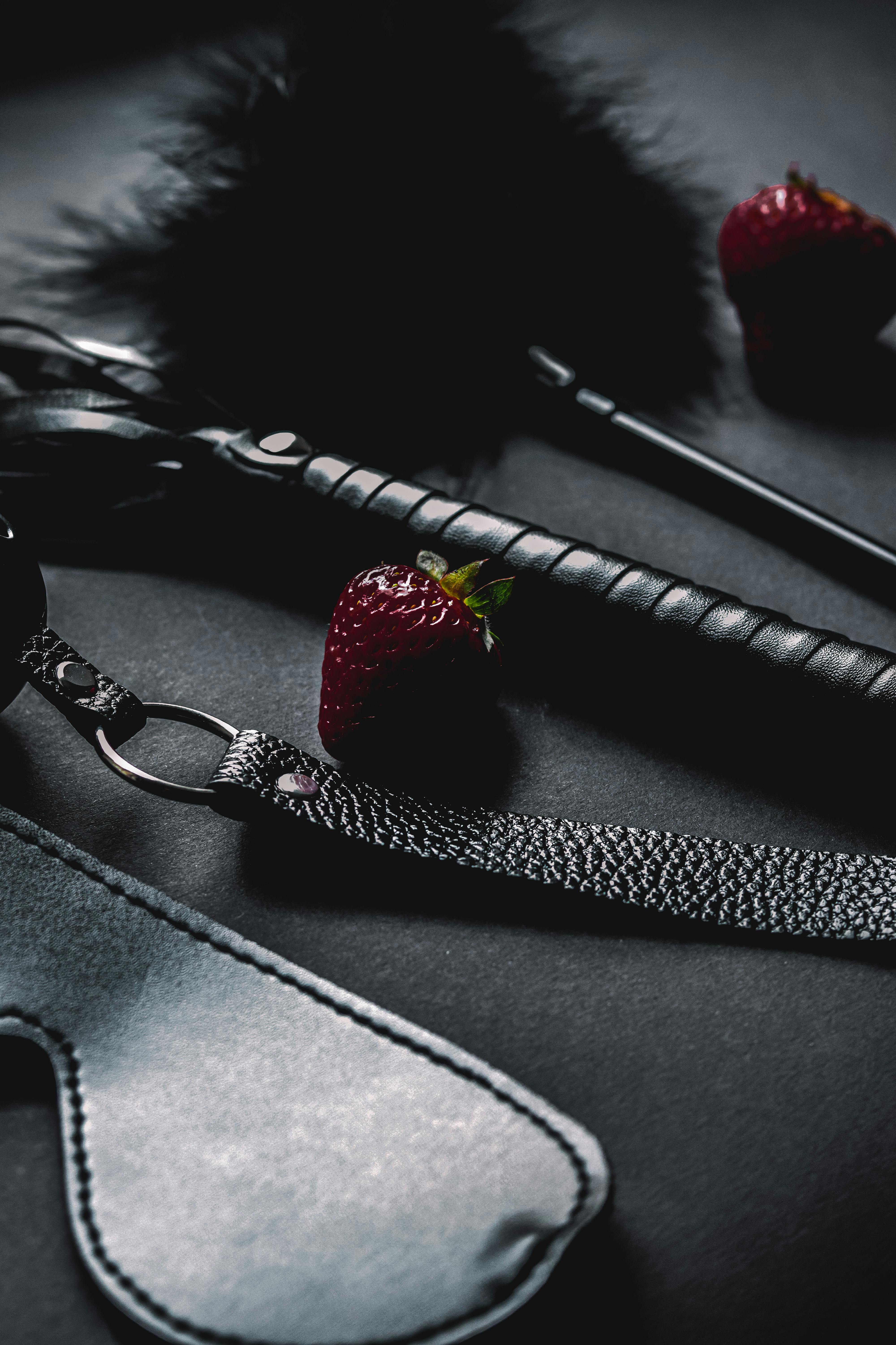 strawberries near black leather sex toys