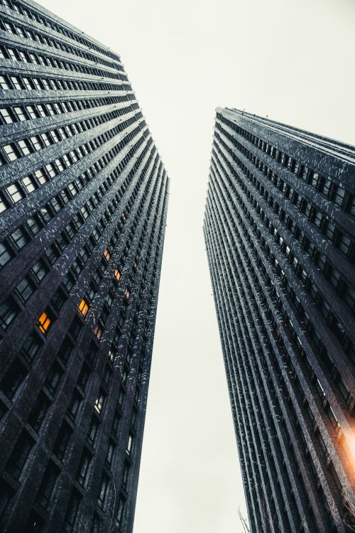 Free Low angle perspective of two towering skyscrapers against a white sky, emphasizing height and architecture. Stock Photo