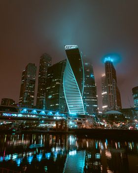 Stunning view of Moscow's cityscape featuring illuminated skyscrapers reflecting in the river at night.
