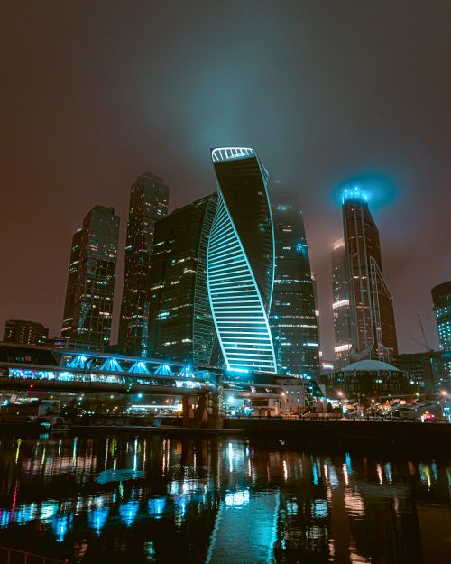 Free Stunning view of Moscow's cityscape featuring illuminated skyscrapers reflecting in the river at night. Stock Photo