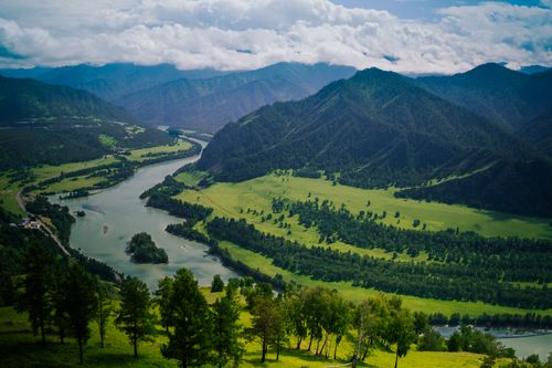 Free A stunning highland scene featuring mountains, a winding river, and lush valleys under a bright sky. Stock Photo