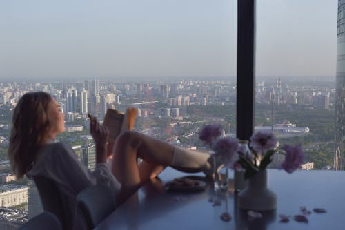 Free Woman Reading a Book on the Dining Table Inside the Apartment Stock Photo