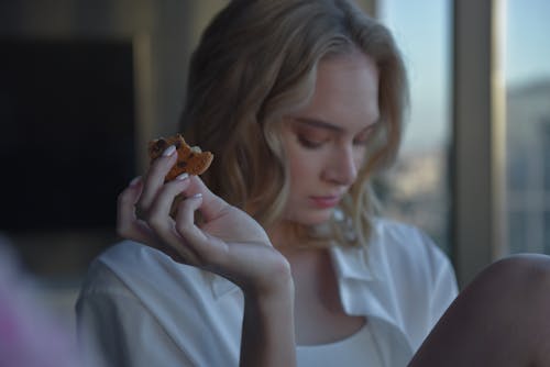 Woman in White Shirt Holding Brown Cookie