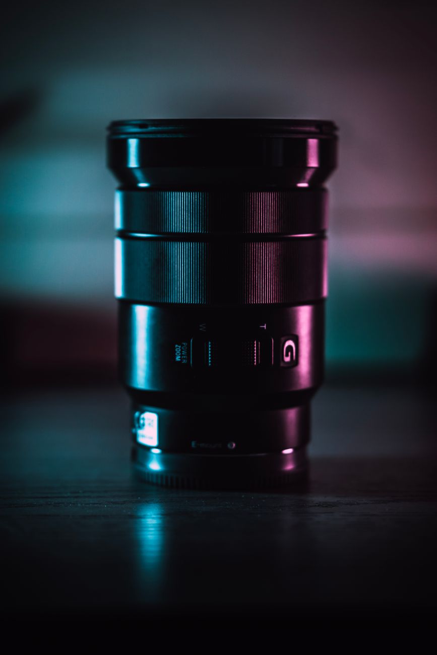 Artistic capture of a camera lens with a moody glow on a dark background.