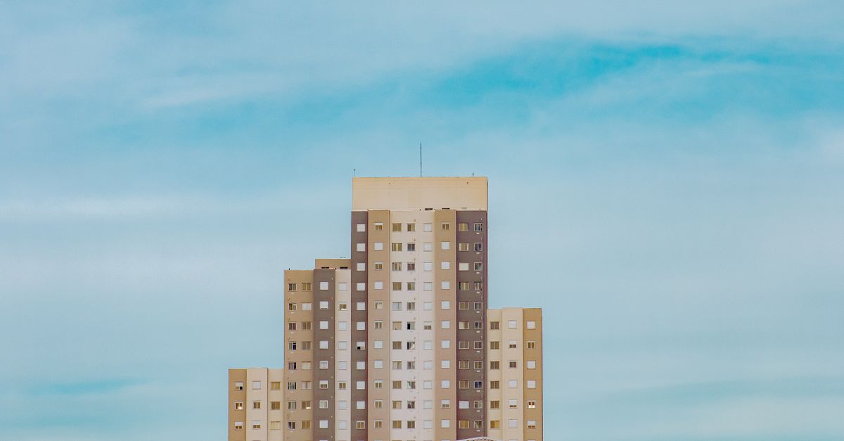 A modern high-rise apartment building under a clear blue sky.
