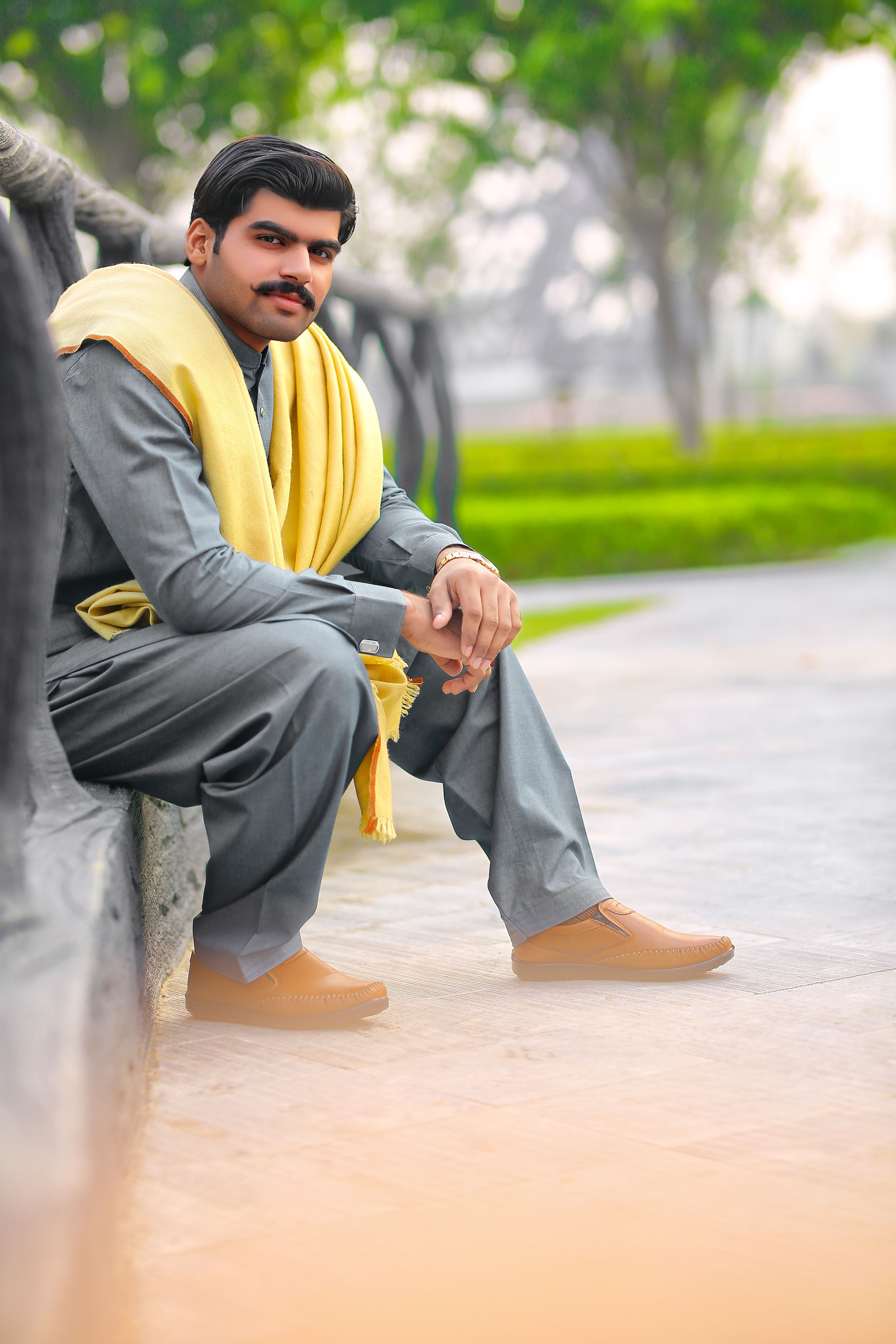 Portrait of a South Asian man in traditional clothing sitting outdoors with a serene expression.