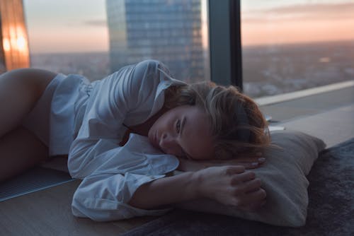 Close Up Photo of Woman in White Long Sleeve Shirt Lying on Pillow