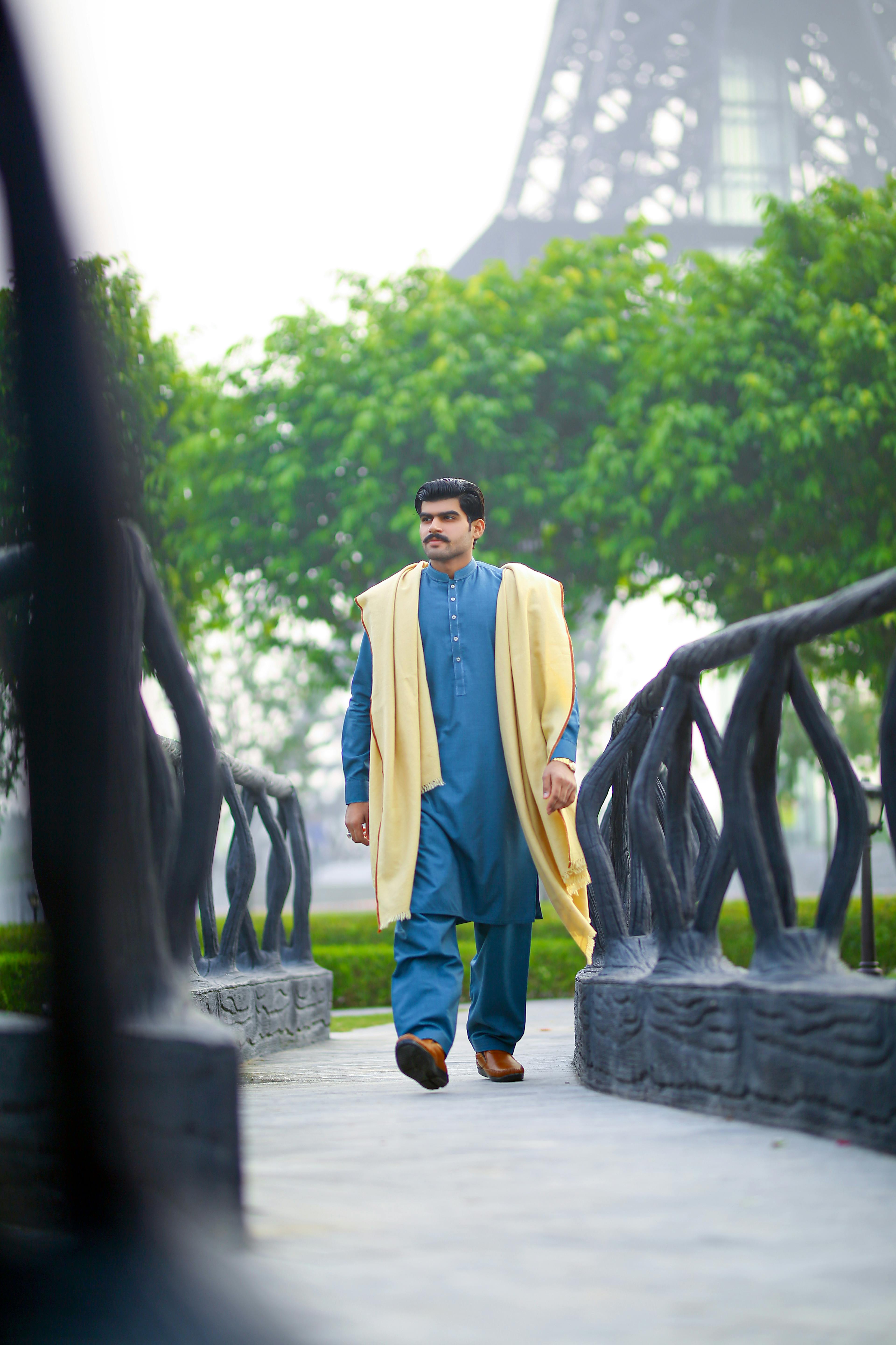man in traditional clothes with yellow shawl walking