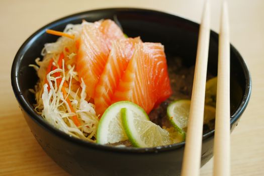 Slices of Salmon Sashimi with Slices of Lime on Black Bowl