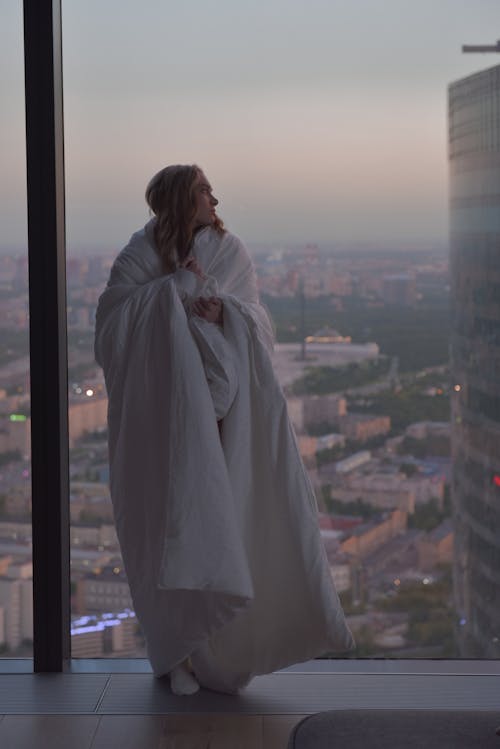 Woman wrapped in White Blanket looking afar 