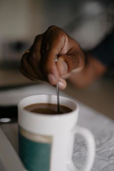 Close-up of a hand stirring coffee in a white mug, creating a cozy feel.