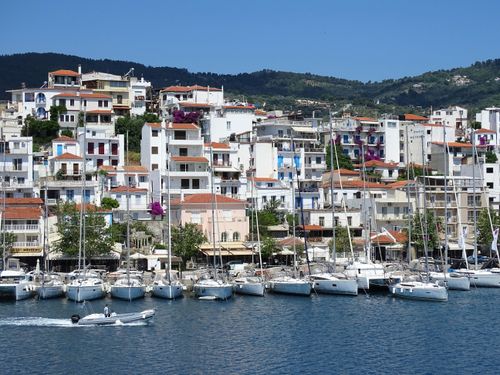 Free Colorful harbor scene in Skiathos, Greece, with docked sailboats against lush hills. Stock Photo