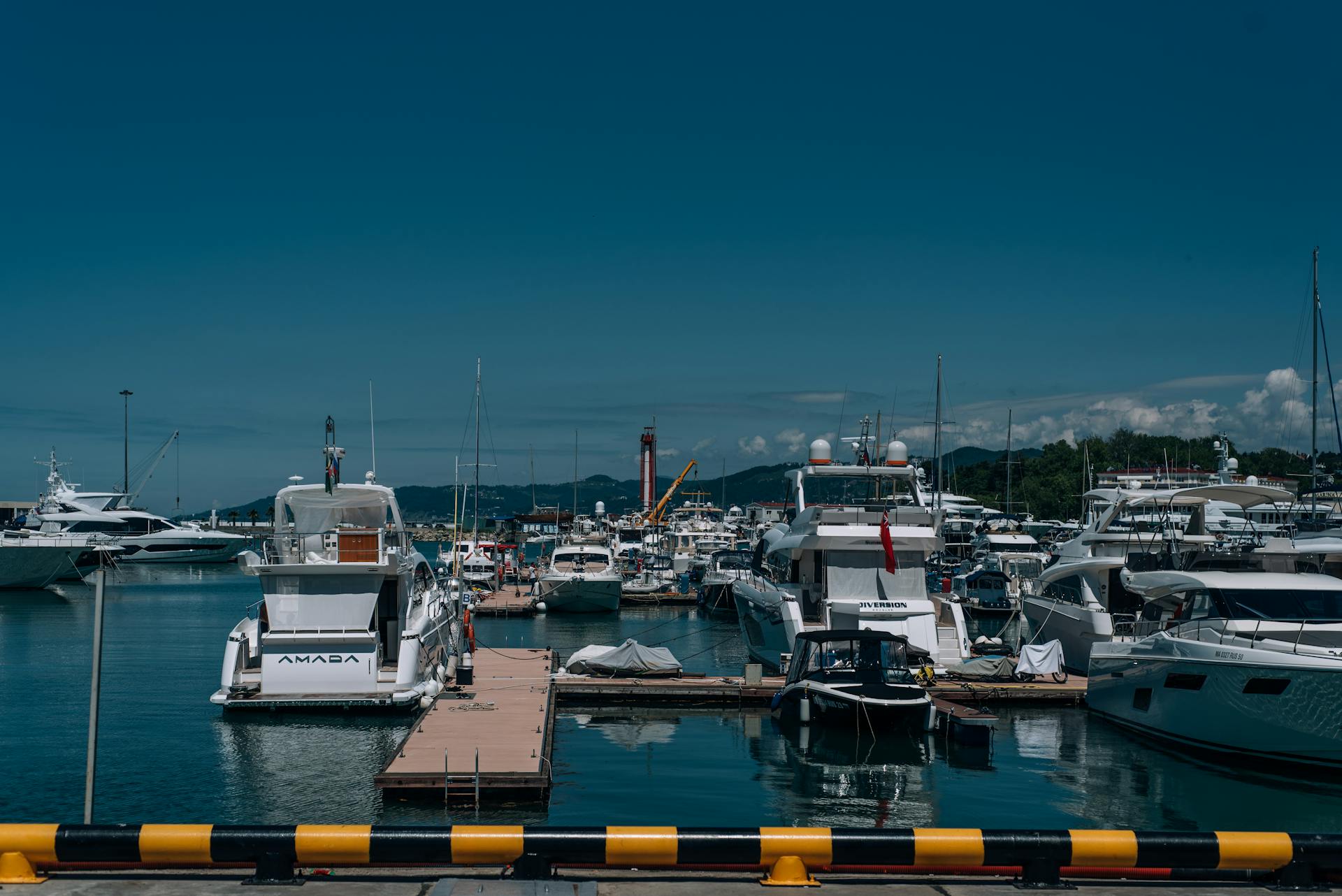A sunny view of yachts docked at a marina in Sochi, Russia, showcasing clear blue skies and calm waters.