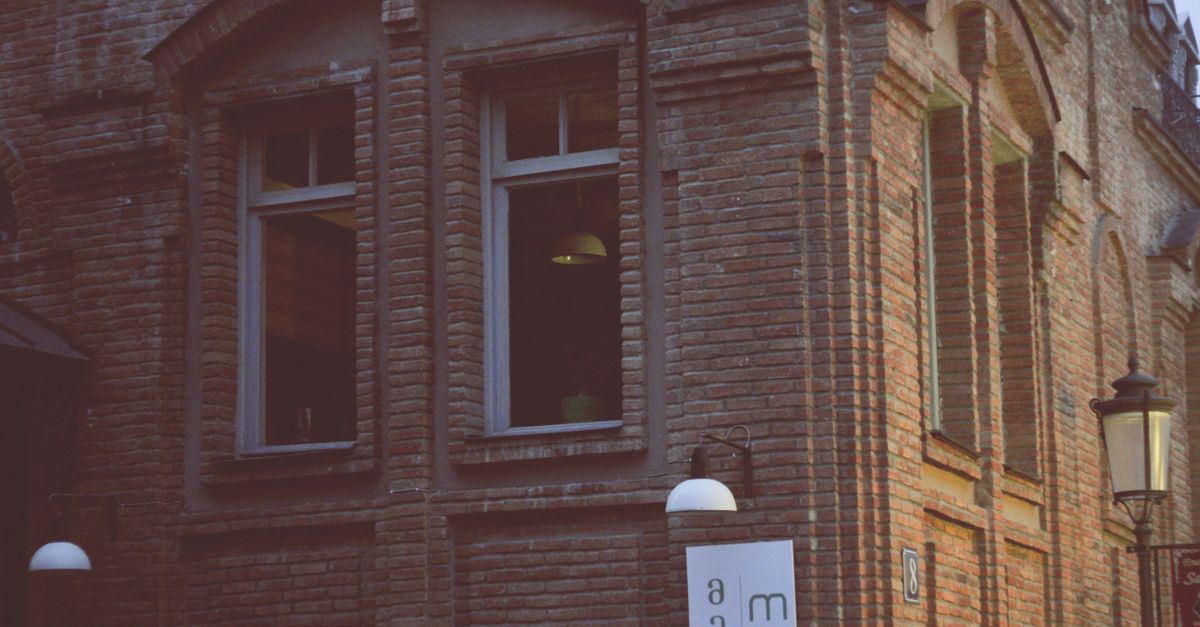 A vintage street lamp complements the brick facade of a historic urban building at dusk.
