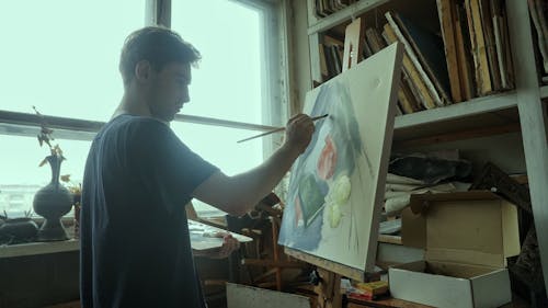A Young Man Painting Near a Glass Window