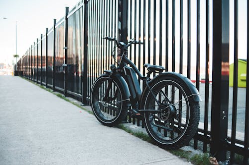 Bicycle Against a Fence Next to Sidewalk 